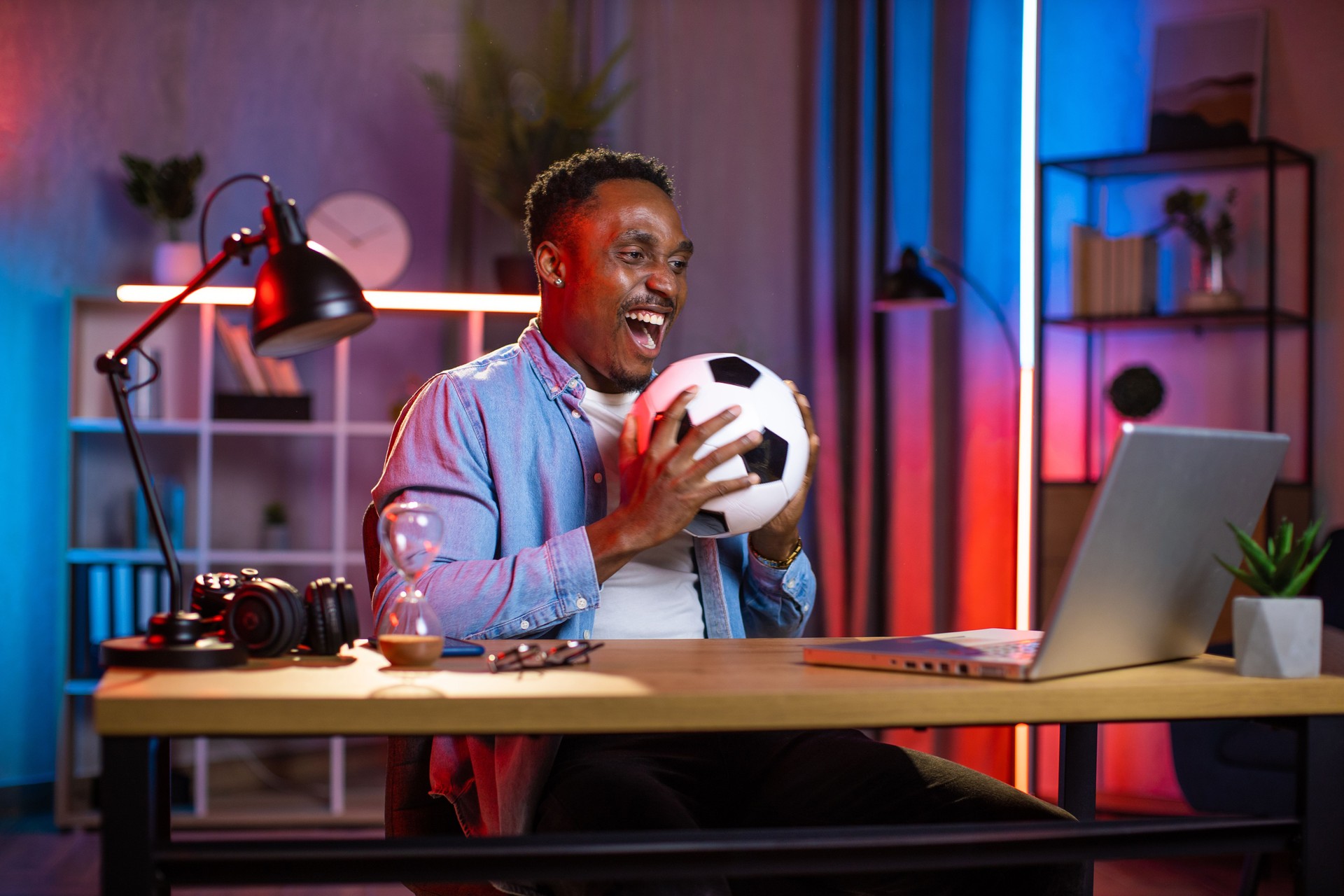 Black-skinned guy, holding ball in hands, happy to watch football game and celebrating winning